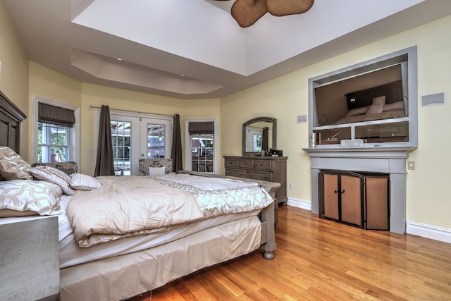 bedroom with hardwood / wood-style flooring, french doors, a raised ceiling, access to outside, and ceiling fan