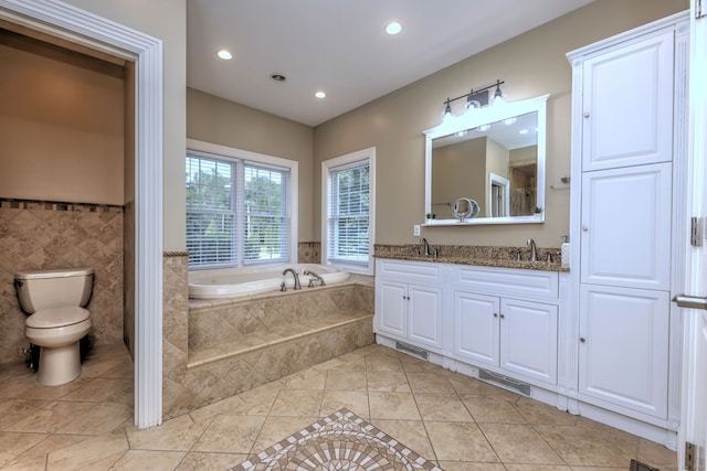 bathroom with tile patterned flooring, toilet, tiled tub, and vanity