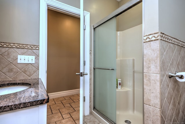 bathroom featuring a shower with shower door, vanity, and tile walls