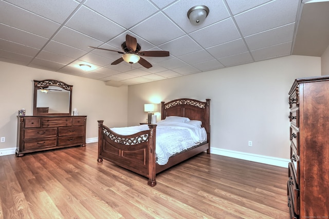 bedroom featuring wood-type flooring, ceiling fan, and a drop ceiling