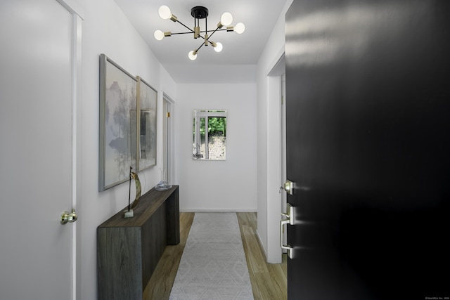 doorway to outside featuring a notable chandelier and light hardwood / wood-style floors