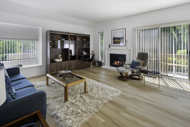 living room with a fireplace, light hardwood / wood-style flooring, and vaulted ceiling