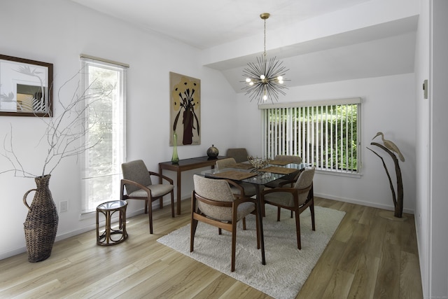 dining room featuring hardwood / wood-style floors, vaulted ceiling, a wealth of natural light, and a notable chandelier