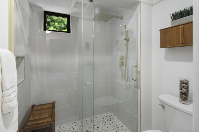 bathroom featuring a shower with shower door and toilet