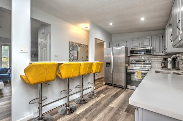 kitchen with appliances with stainless steel finishes, dark hardwood / wood-style flooring, lofted ceiling, and sink