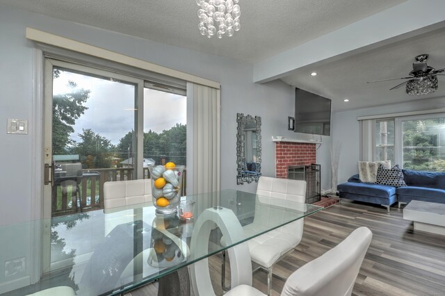 dining area featuring beam ceiling, a fireplace, wood-type flooring, and a textured ceiling