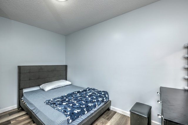 bedroom with dark hardwood / wood-style floors and a textured ceiling