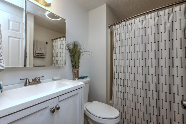 bathroom featuring toilet, vanity, and a textured ceiling