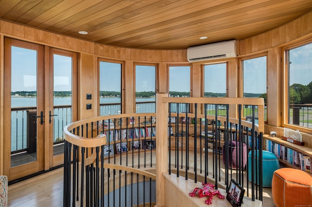 215 Uncas Point Rd, Guilford, CT 06437 - sunroom with a wall mounted AC, wooden walls, a water view, wooden ceiling, and wood finished floors