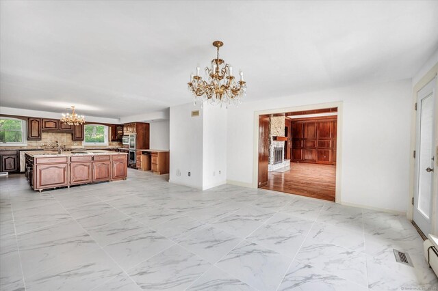 interior space with backsplash, a notable chandelier, sink, and light wood-type flooring