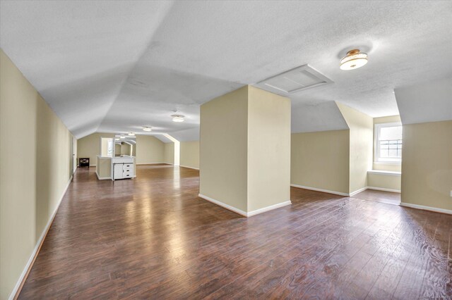 bonus room with vaulted ceiling, hardwood / wood-style floors, and a textured ceiling