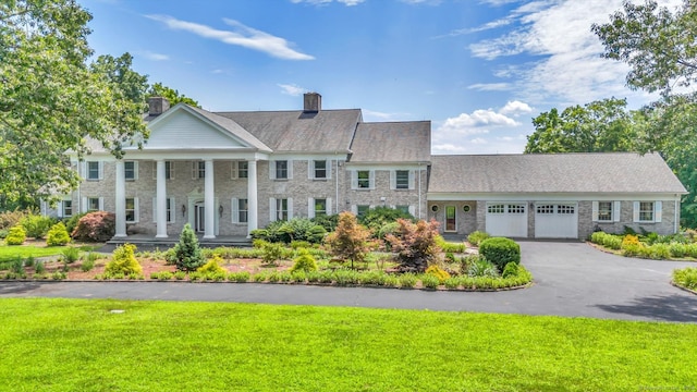 greek revival inspired property with a garage and a front yard