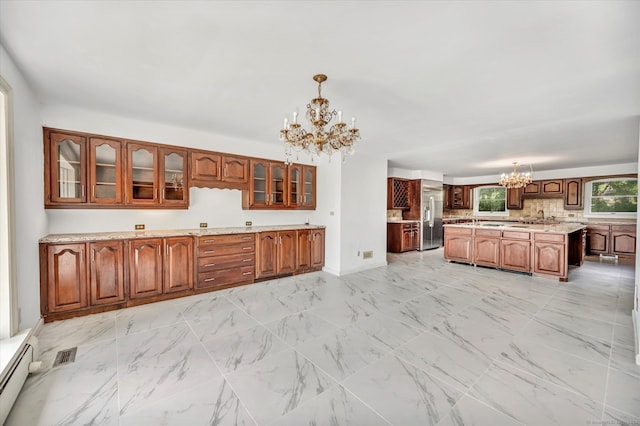 kitchen with a kitchen island with sink, a chandelier, decorative light fixtures, and light tile patterned floors