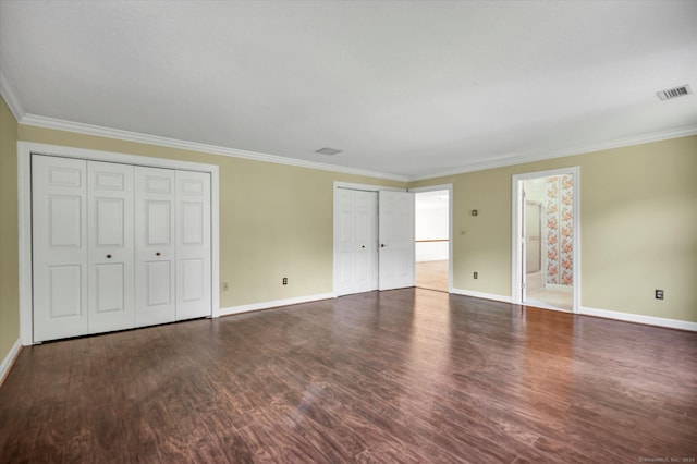 unfurnished bedroom featuring multiple closets, crown molding, connected bathroom, and hardwood / wood-style floors