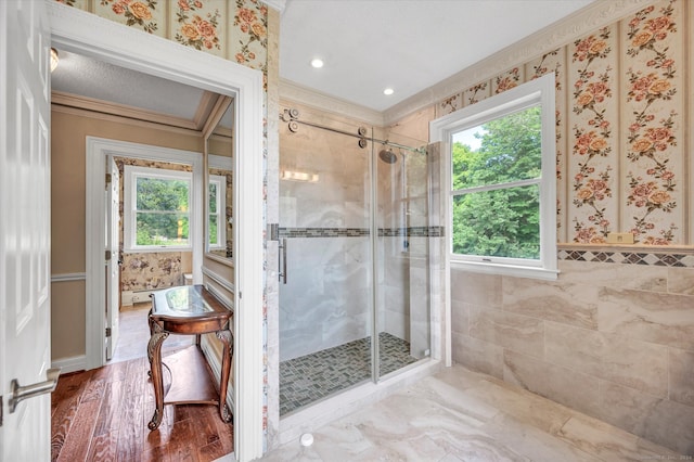 bathroom featuring a shower with shower door, hardwood / wood-style floors, a wealth of natural light, and ornamental molding