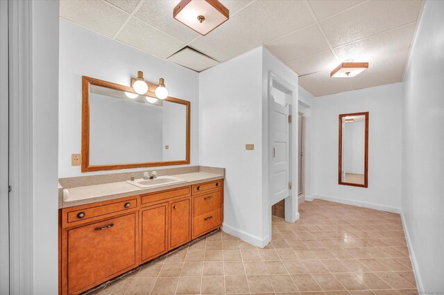 bathroom featuring vanity, tile patterned flooring, and a drop ceiling