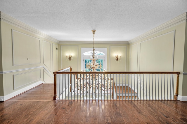 hall with an inviting chandelier, a textured ceiling, crown molding, and dark hardwood / wood-style floors