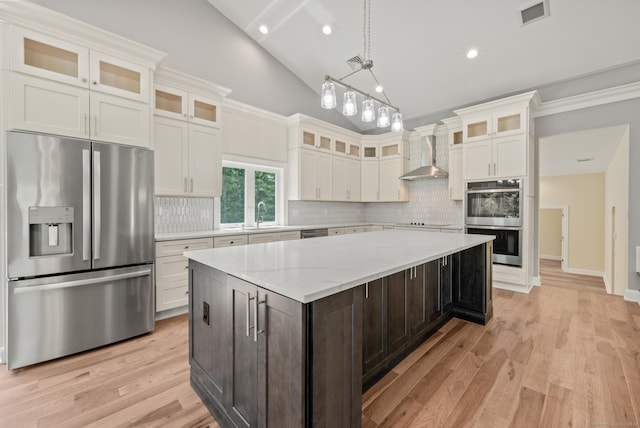 kitchen with white cabinetry, wall chimney exhaust hood, stainless steel appliances, dark brown cabinets, and a kitchen island