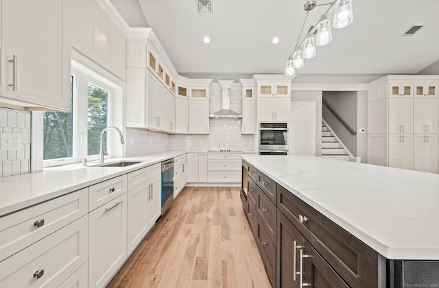 kitchen featuring white cabinets, wall chimney exhaust hood, dark brown cabinets, and appliances with stainless steel finishes