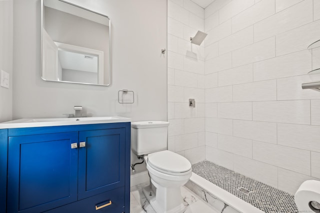 bathroom with a tile shower, vanity, and toilet