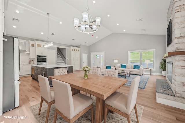 dining space with light hardwood / wood-style flooring, high vaulted ceiling, and an inviting chandelier