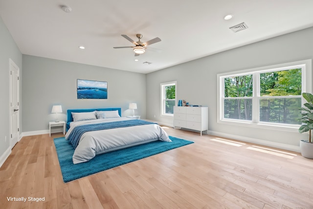 bedroom with multiple windows, light hardwood / wood-style flooring, and ceiling fan