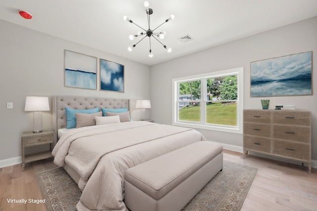 bedroom with light hardwood / wood-style flooring and a chandelier