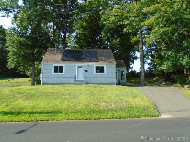 cape cod home featuring solar panels and a front yard