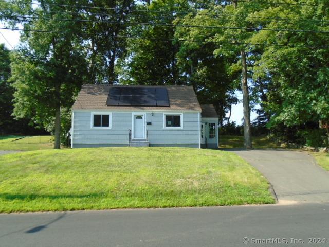 cape cod-style house with solar panels and a front lawn