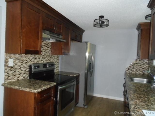 kitchen with decorative backsplash, under cabinet range hood, a sink, stainless steel electric range oven, and baseboards