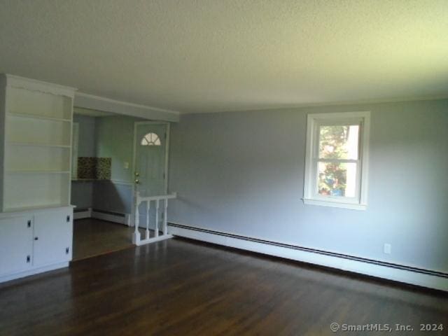 spare room featuring wood finished floors and baseboard heating