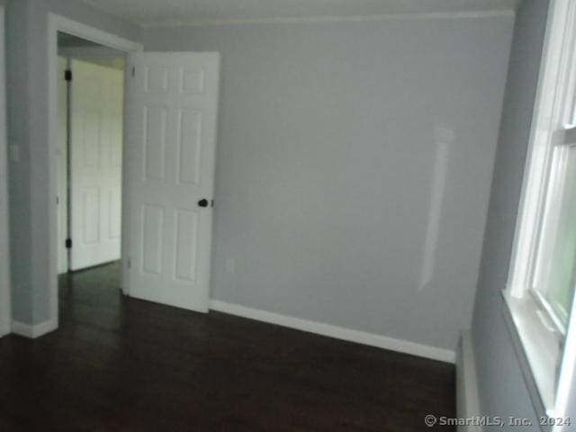 empty room with dark wood-style floors and baseboards