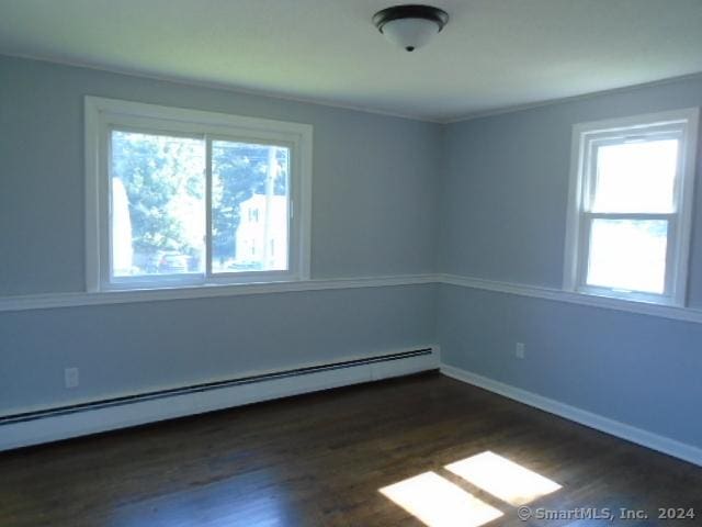 unfurnished room featuring a baseboard heating unit, dark wood-type flooring, and baseboards