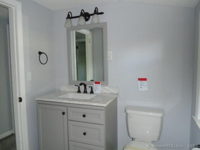 half bathroom featuring vanity and toilet