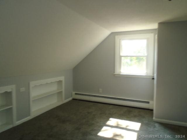 additional living space featuring built in shelves, baseboards, lofted ceiling, baseboard heating, and carpet flooring