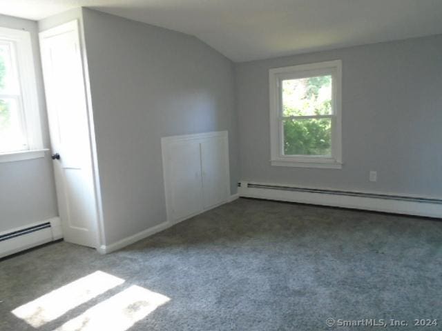 spare room with vaulted ceiling, carpet flooring, and a baseboard radiator