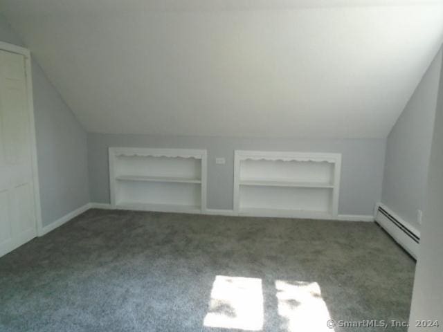 additional living space featuring a baseboard heating unit, lofted ceiling, built in shelves, and carpet floors