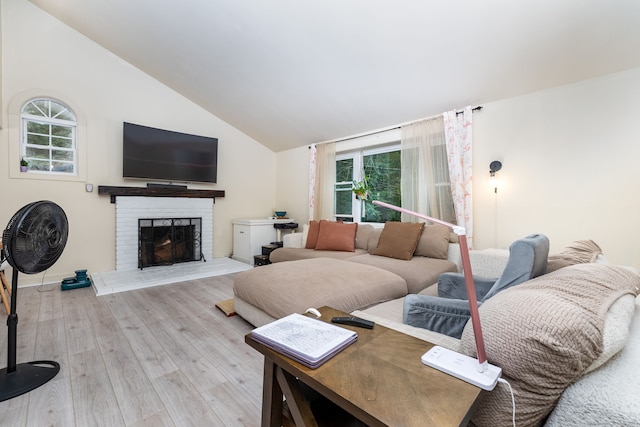 living room featuring a brick fireplace, light wood-type flooring, and vaulted ceiling