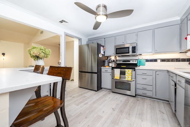 kitchen featuring decorative backsplash, light hardwood / wood-style floors, crown molding, and stainless steel appliances