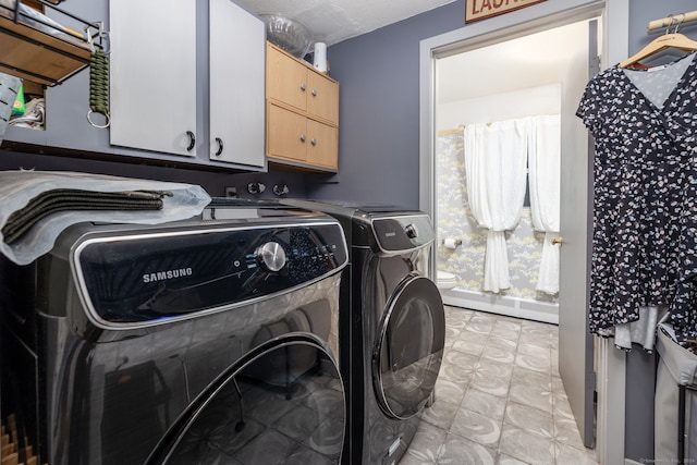 laundry room with a baseboard heating unit, washing machine and clothes dryer, and cabinets