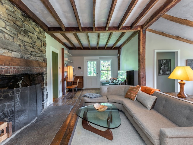 living room with vaulted ceiling with beams, a stone fireplace, and hardwood / wood-style floors