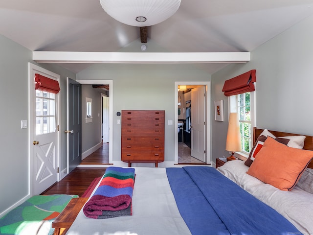 bedroom with vaulted ceiling, multiple windows, and dark hardwood / wood-style flooring