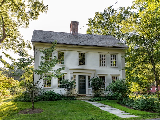 colonial-style house featuring a front lawn