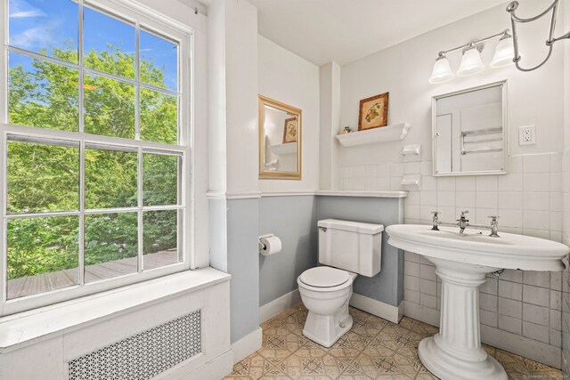 bathroom featuring tile walls, decorative backsplash, radiator heating unit, toilet, and tile patterned floors