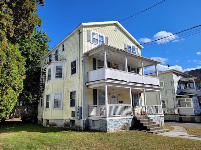 view of front of property with a balcony, covered porch, and a front yard