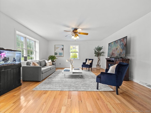 living room featuring light hardwood / wood-style flooring, ceiling fan, and a healthy amount of sunlight