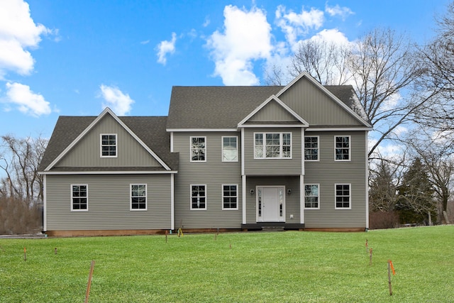 view of front facade with a front lawn and a shingled roof