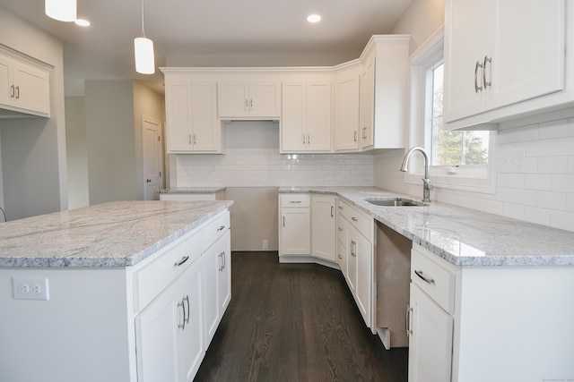 kitchen featuring dark wood-type flooring, white cabinets, light stone counters, and a sink