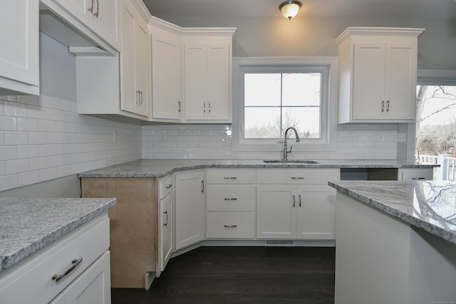 kitchen with a sink, dark wood-style floors, backsplash, and a wealth of natural light