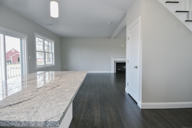 interior space featuring a fireplace, dark wood-style floors, baseboards, and light stone countertops